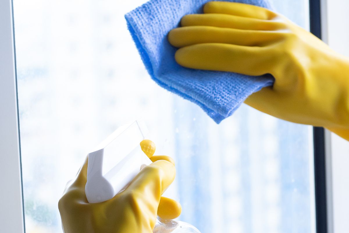  An individual in yellow rubber gloves is engaged in the task of cleaning a window, promoting a bright and tidy environment.