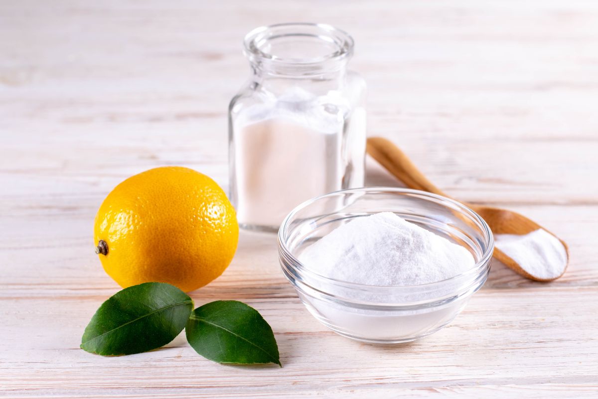 A wooden table displaying a lemon, sugar, and salt arranged aesthetically for a culinary setting. 